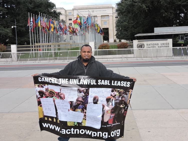 Campaign Manager Eddie Tanago outside the United Nations building in Geneva with a stop the SABL land grab banner